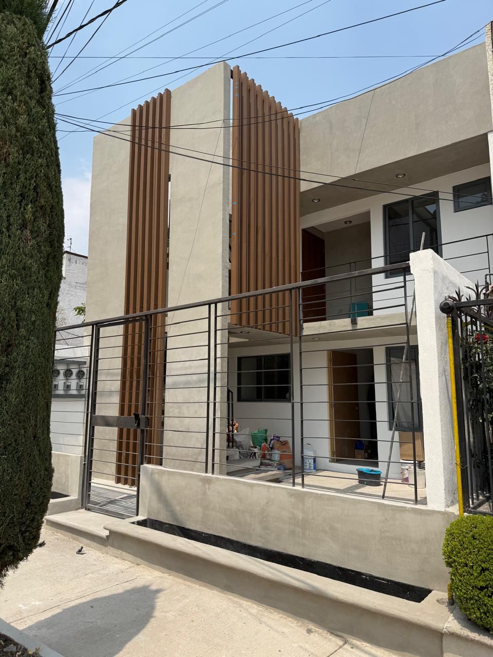 Fachada de la casa con muros de acabado gris y lamas de madera