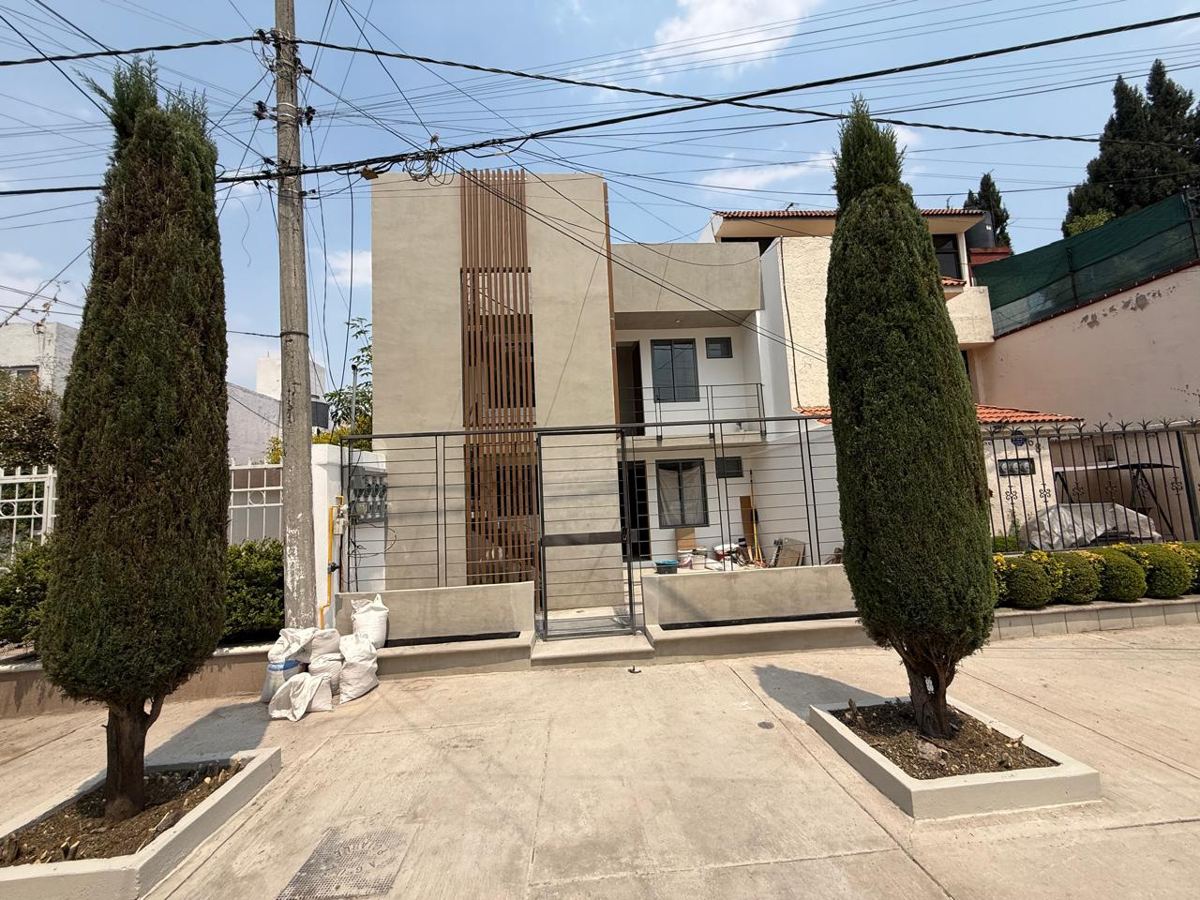 Fachada de una casa habitacional con celosía de lamas de madera y herrería en la calle